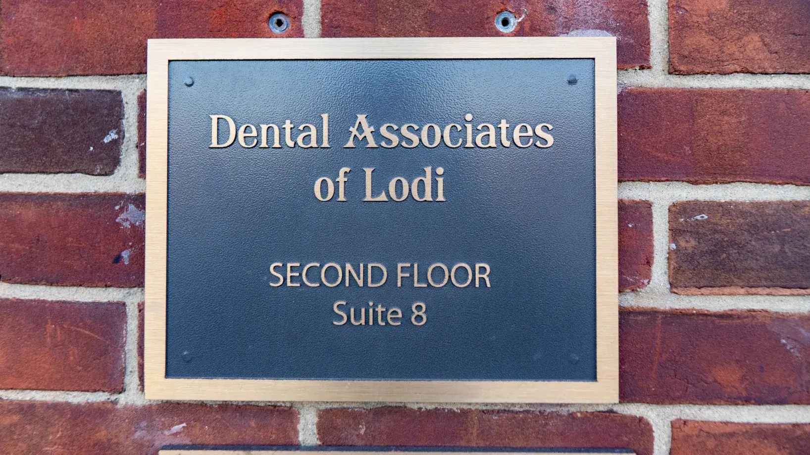 Plaque on brick wall reads: "Dental Associates of Lodi, Second Floor, Suite 8."
