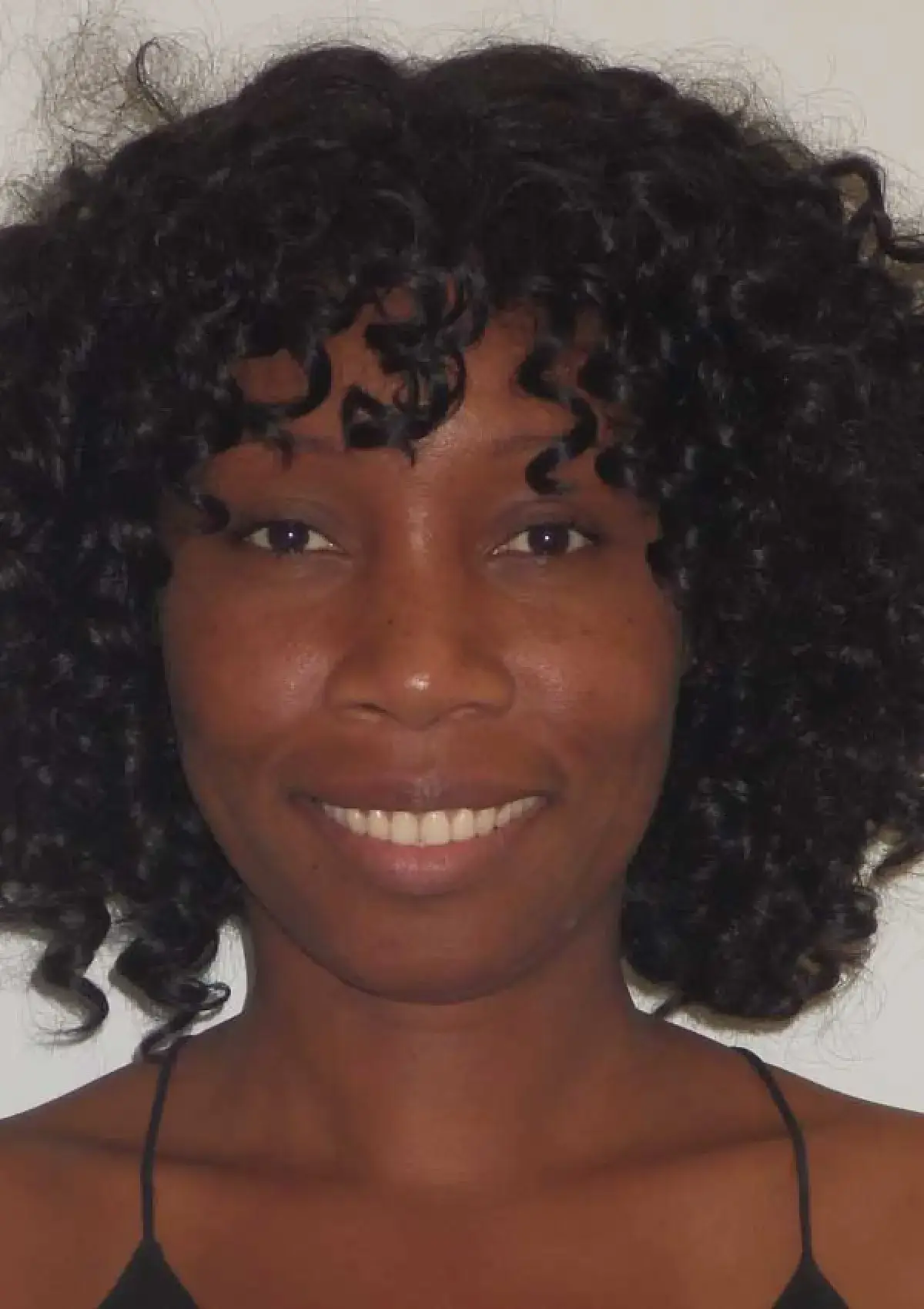 A person with curly hair smiling at the camera.