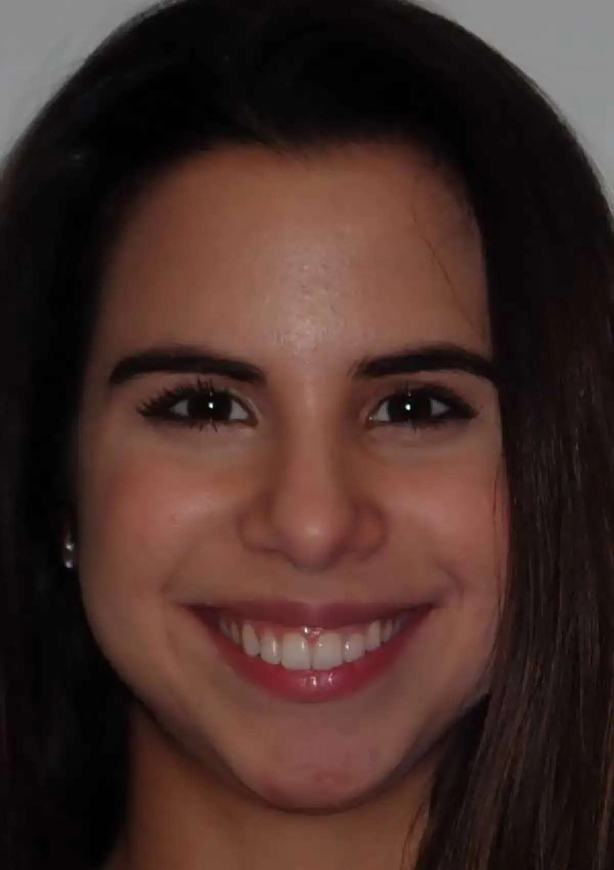 Smiling person with long brown hair and visible teeth, looking directly at the camera.