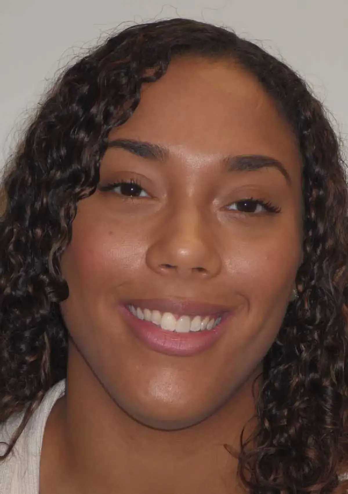 A person with curly hair smiling at the camera.