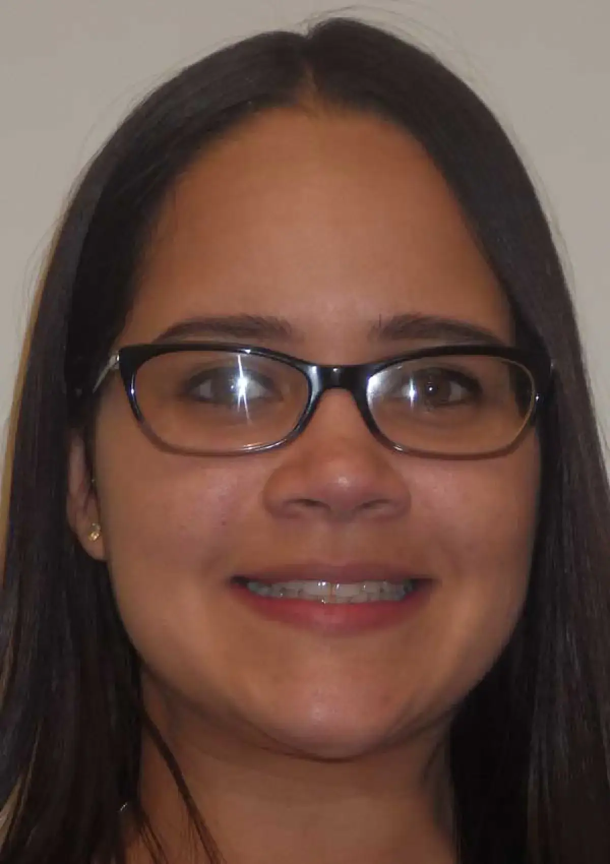 A person with long hair and glasses is smiling at the camera.