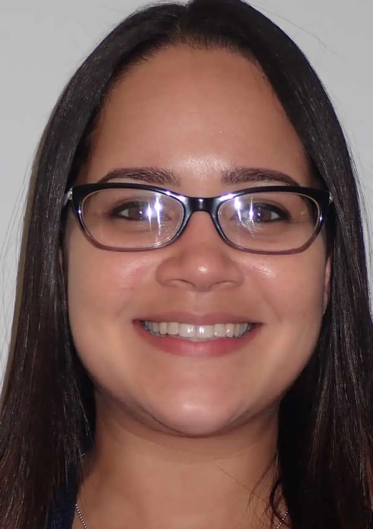 A person with long hair and glasses is smiling at the camera.