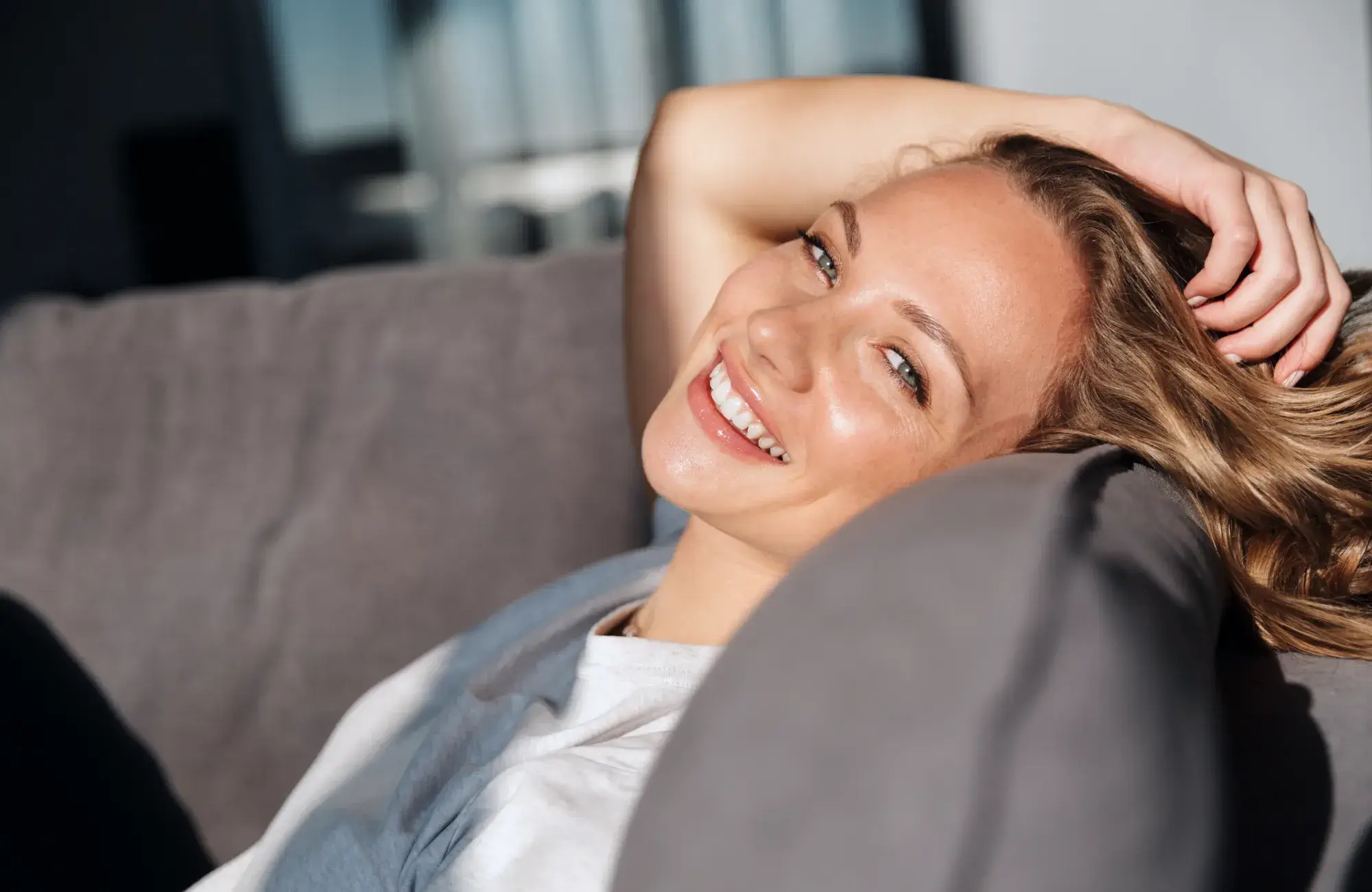 A person lounging on a sofa, smiling and looking relaxed.