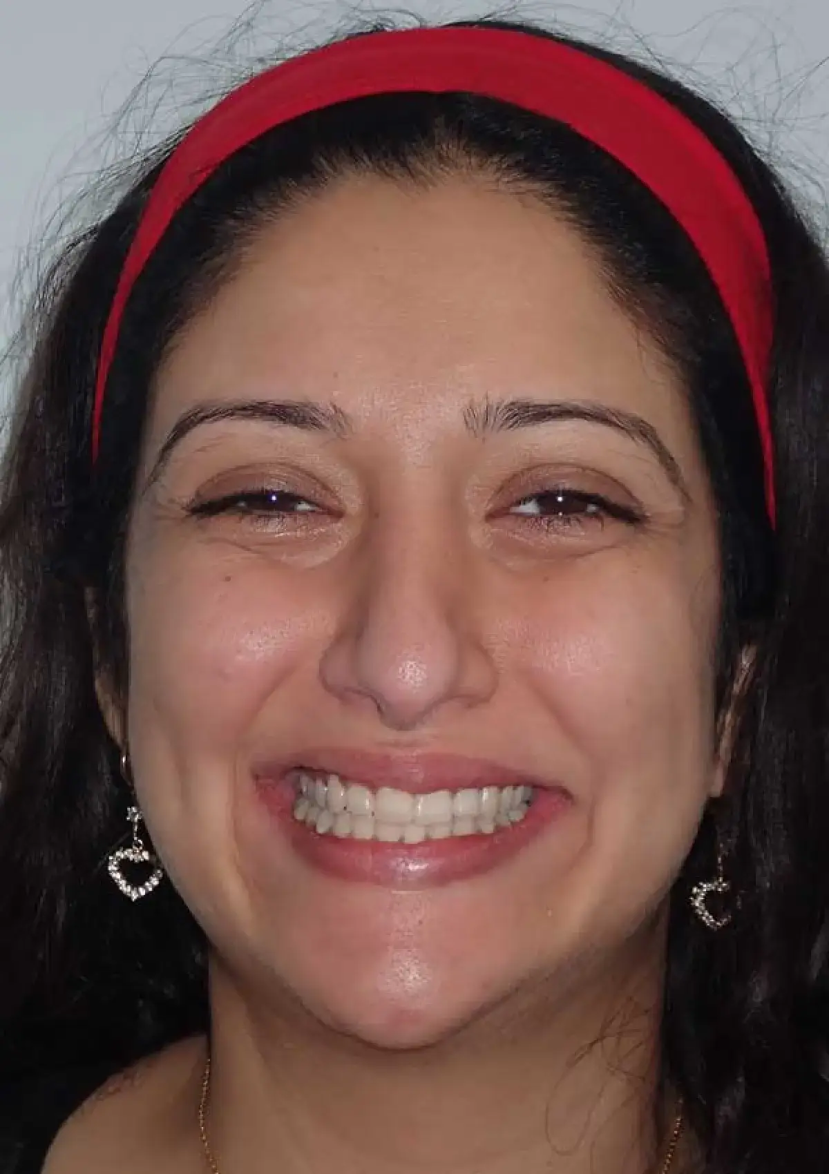 A person with a red headband is smiling at the camera.