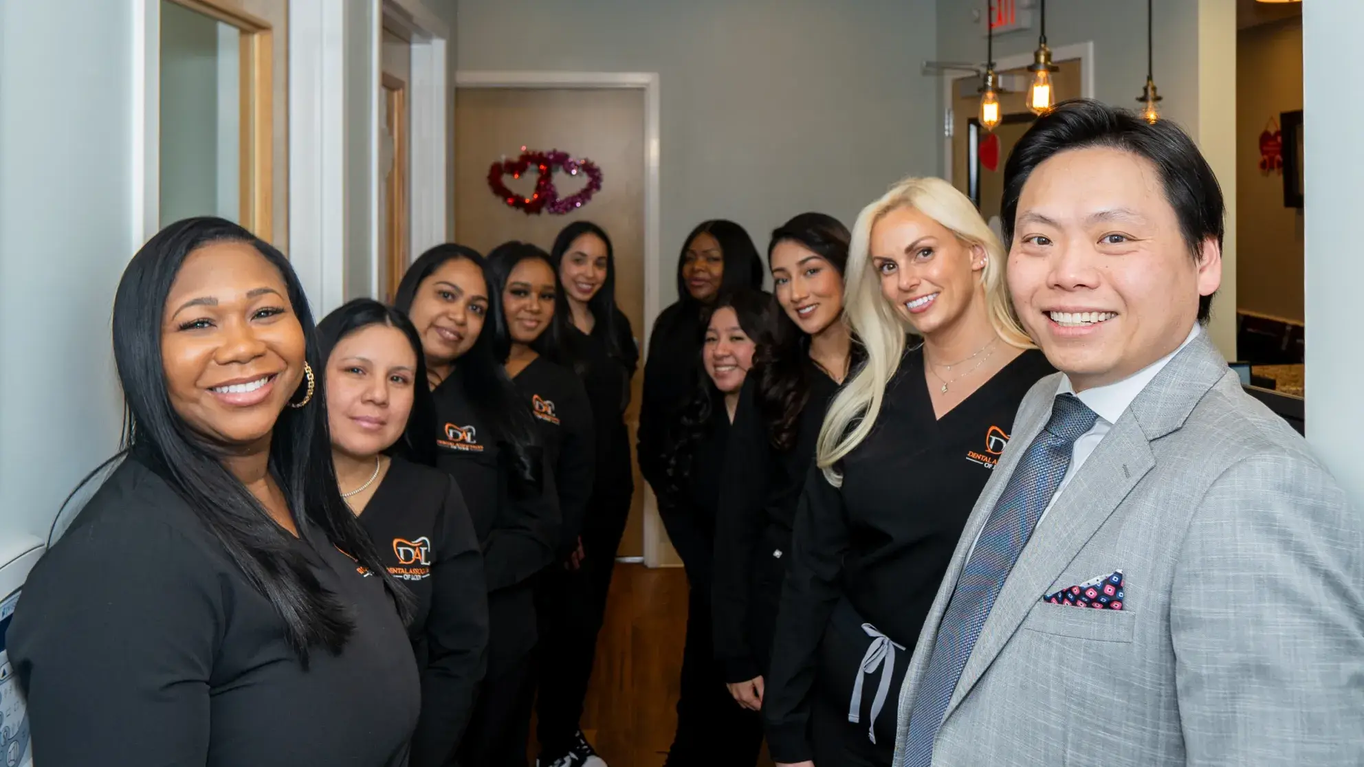 A group of people wearing black uniforms and a man in a suit stand in a hallway.