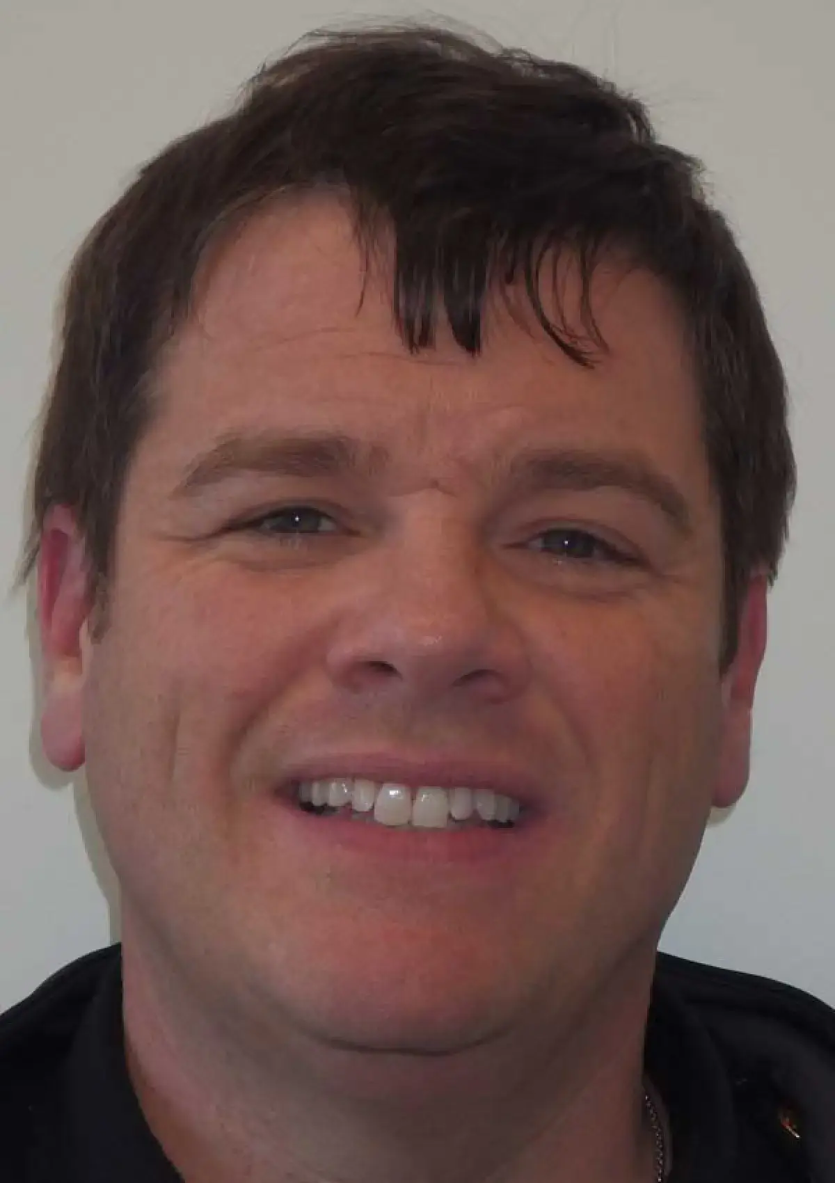 A person with short dark hair is smiling at the camera.