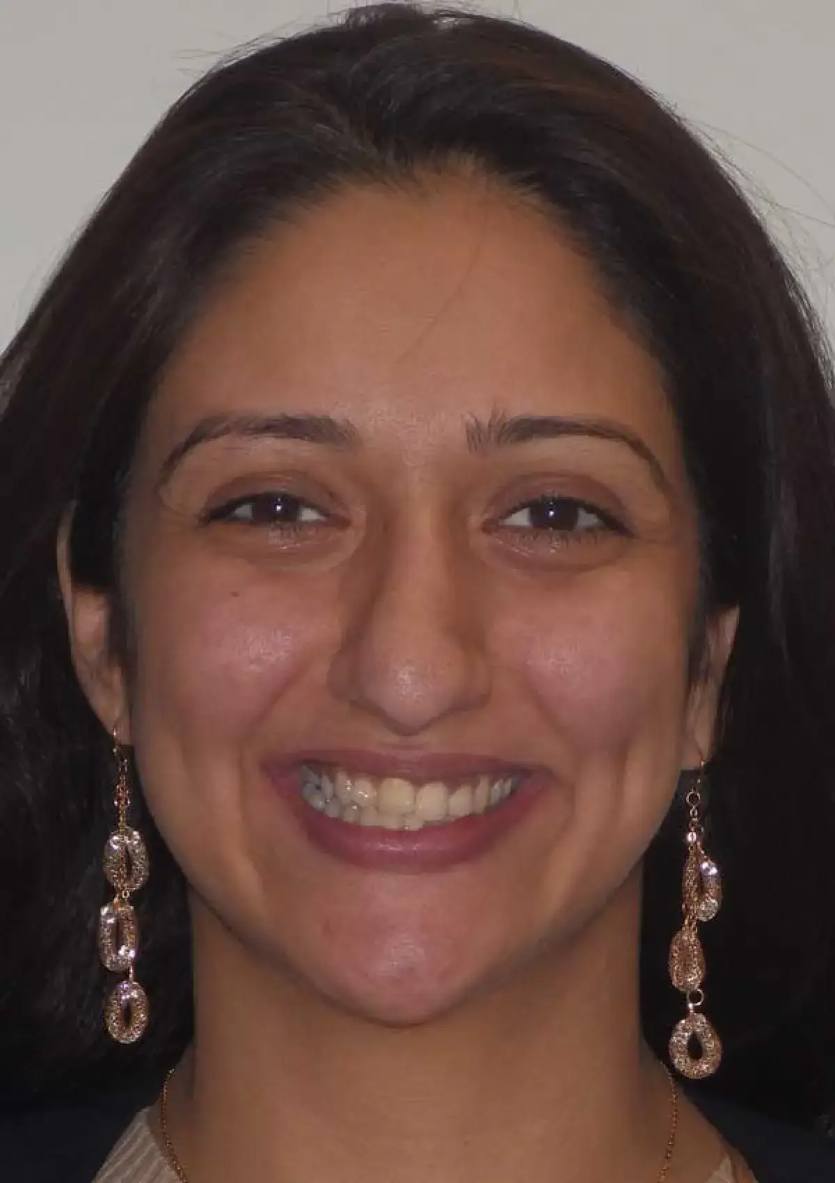 Smiling woman with long hair and dangling earrings facing the camera.