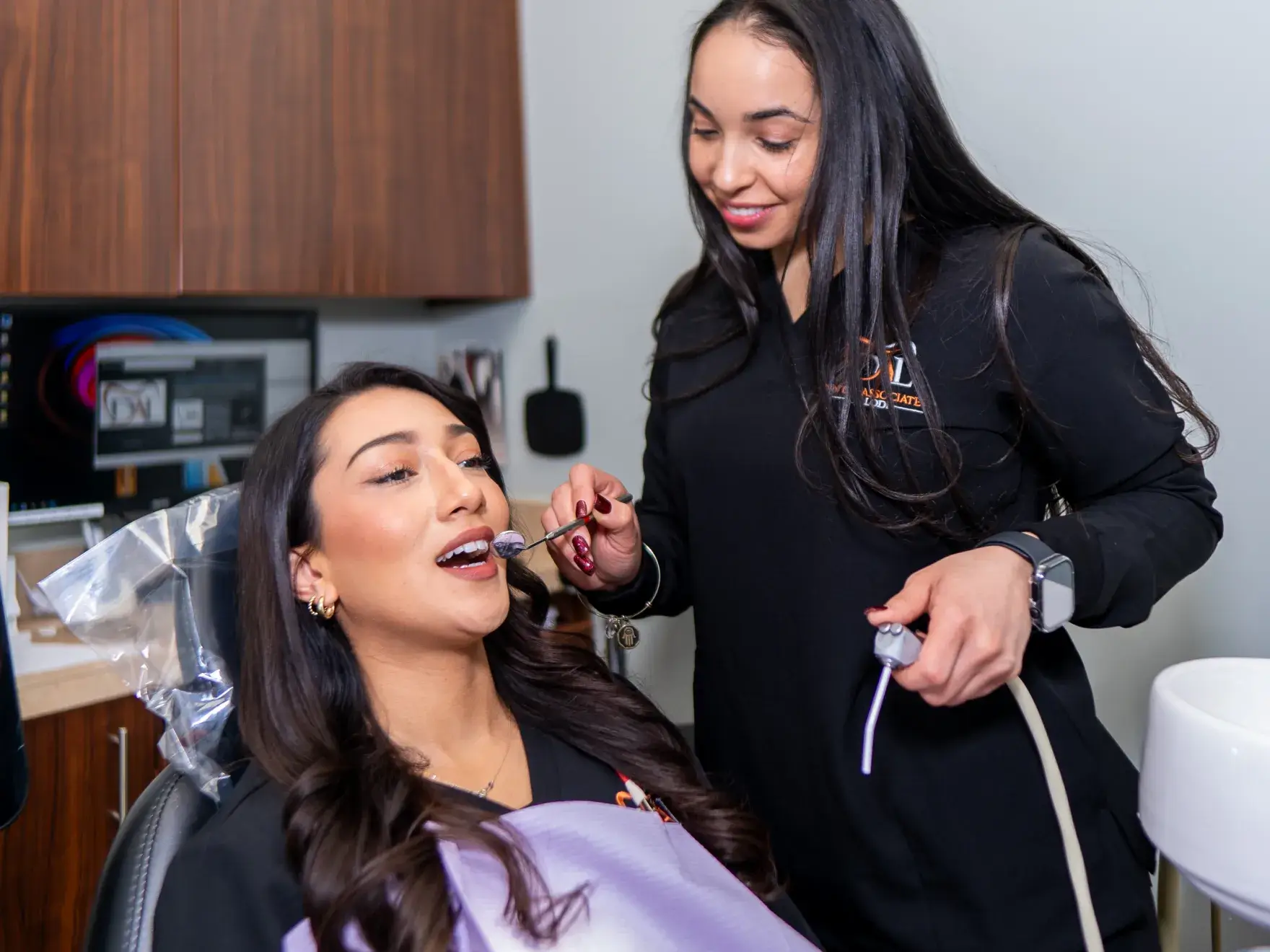 A dental professional examines a patient sitting in a dentist's chair.