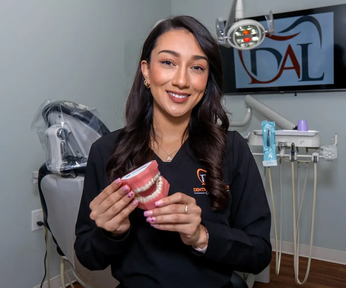 Smiling female dentist holding a dental model in a dental clinic.