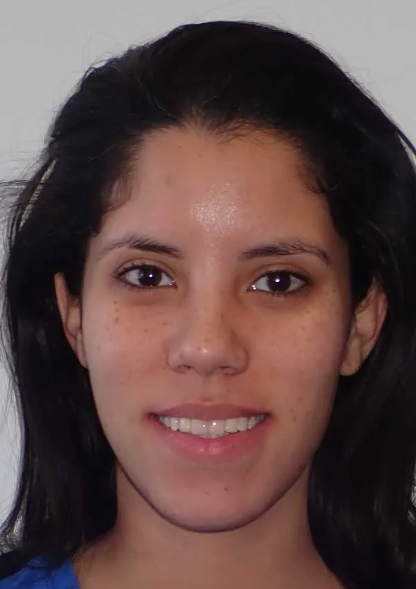 A person with long dark hair is smiling at the camera against a neutral background.