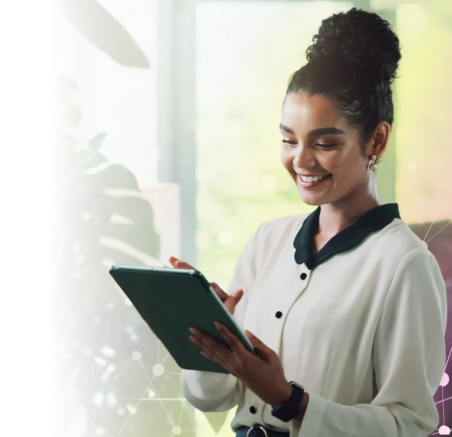 Smiling woman using a tablet indoors with green plant and bright window background.