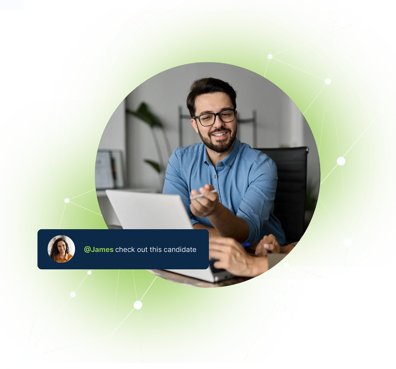 Smiling man in glasses points to laptop screen during discussion with another person.