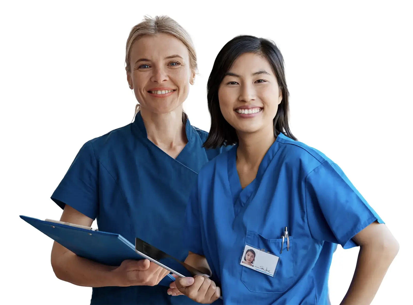 Two smiling female healthcare workers in blue scrubs holding a clipboard and tablet.