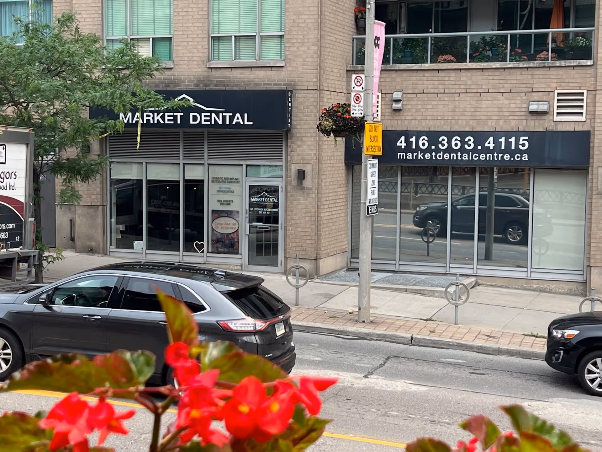Street view of Market Dental office with parked cars and red flowers in foreground.