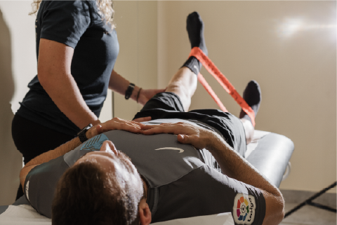 Sesión de fisioterapia y recuperación funcional, donde el paciente realiza ejercicios asistidos con banda elástica para mejorar movilidad, fuerza y control de la extremidad inferior.