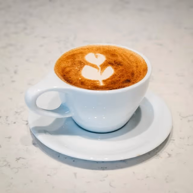 A cup of coffee with a heart shaped foam on top.