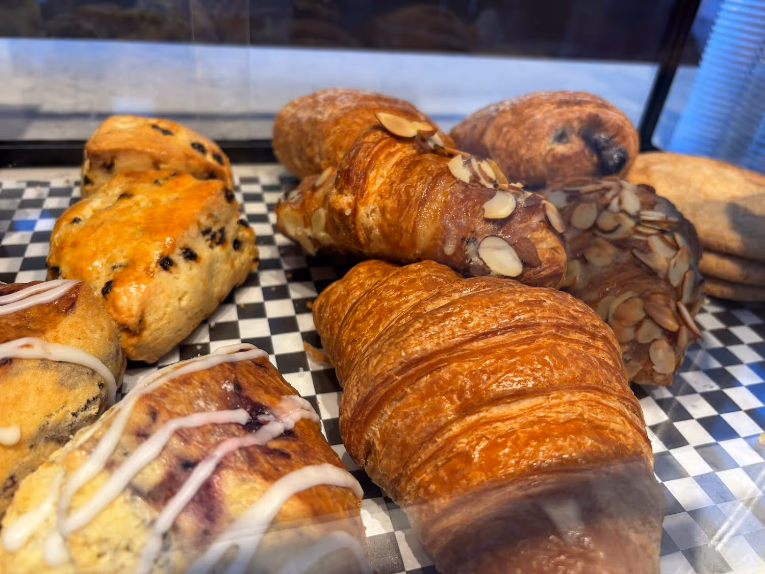 A bakery case filled with a variety of pastries, including croissants, tarts, and cakes, all looking scrumptious.