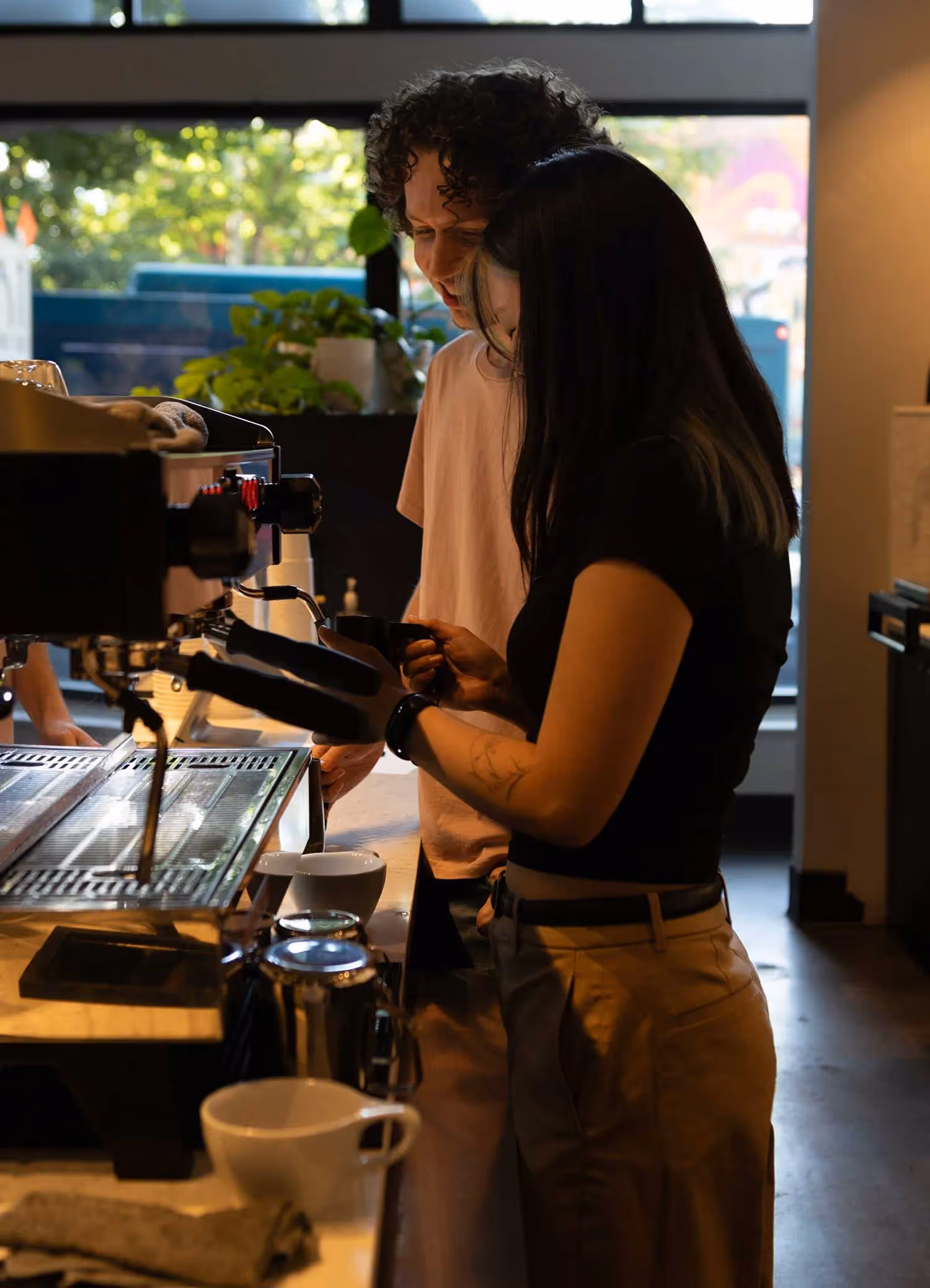 A man and woman standing in front of a coffee machine.