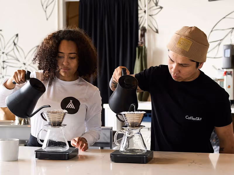 A man and woman are making coffee together.