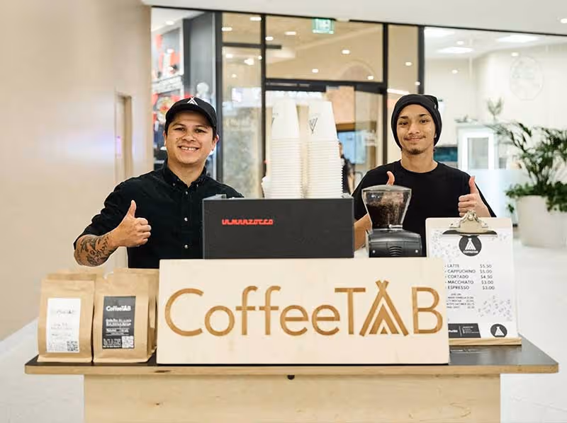 Two men standing behind a coffee shop counter.