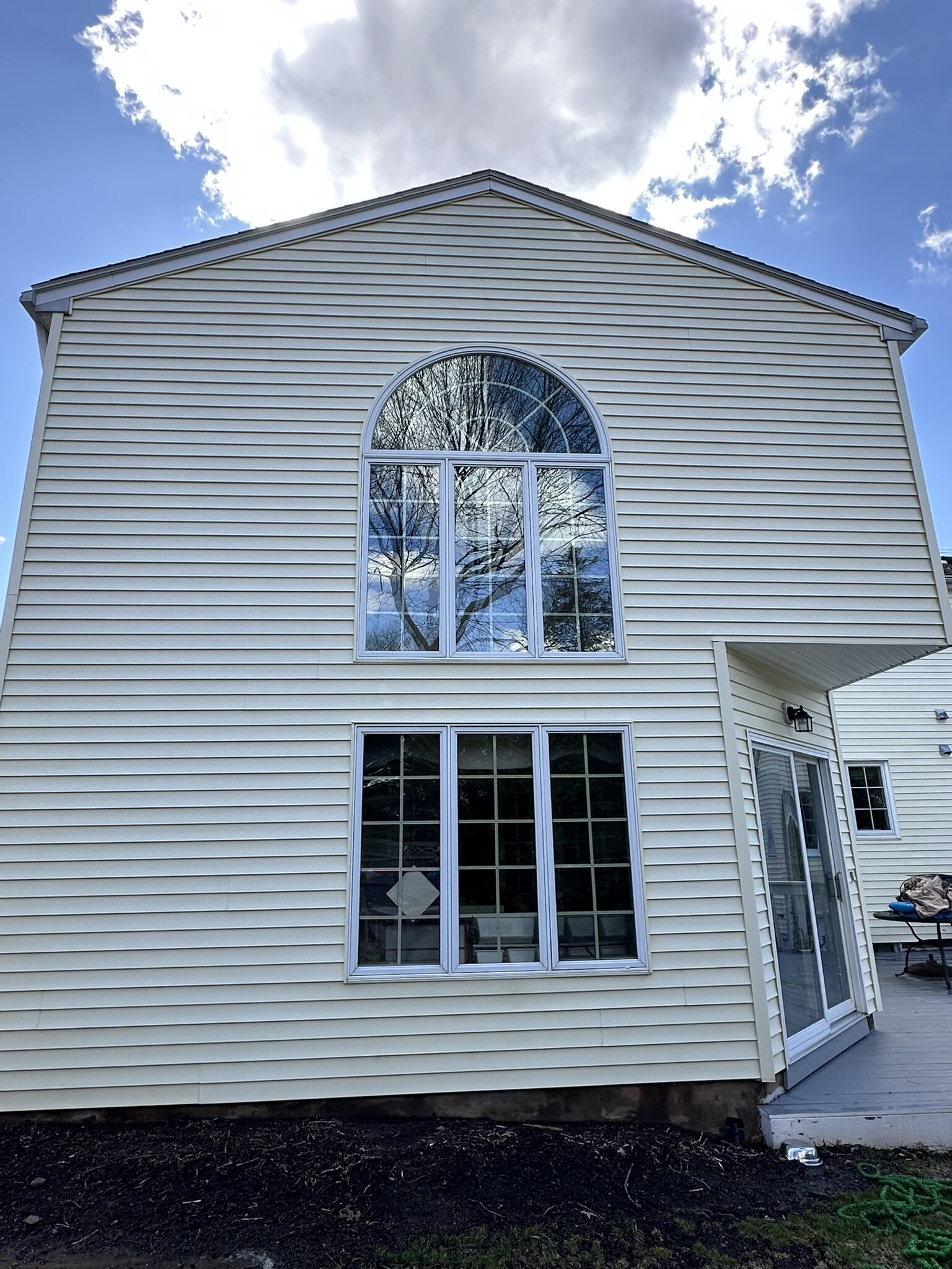 Bright clean cream siding on a two-story gable after soft wash
