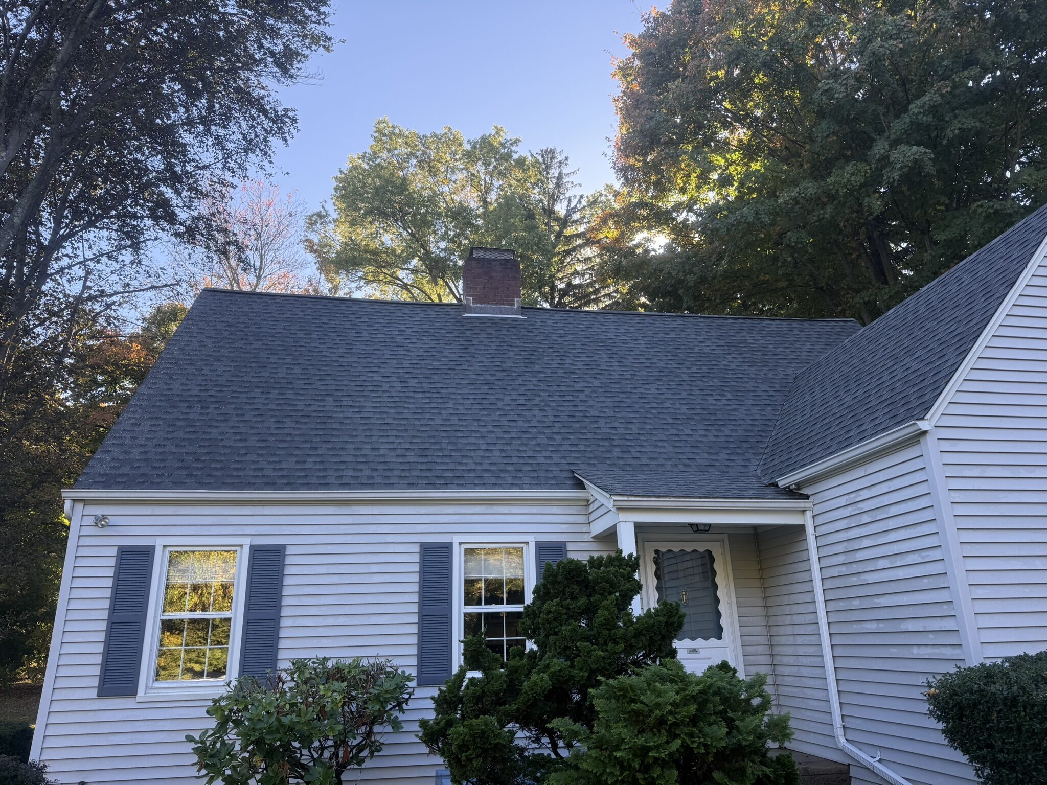 Clean asphalt roof on a white cape-style home after soft wash