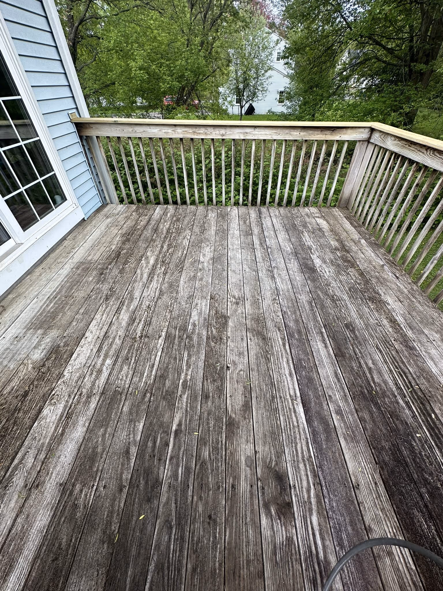 Wood deck with railing cleaned and brightened, overlooking a green backyard
