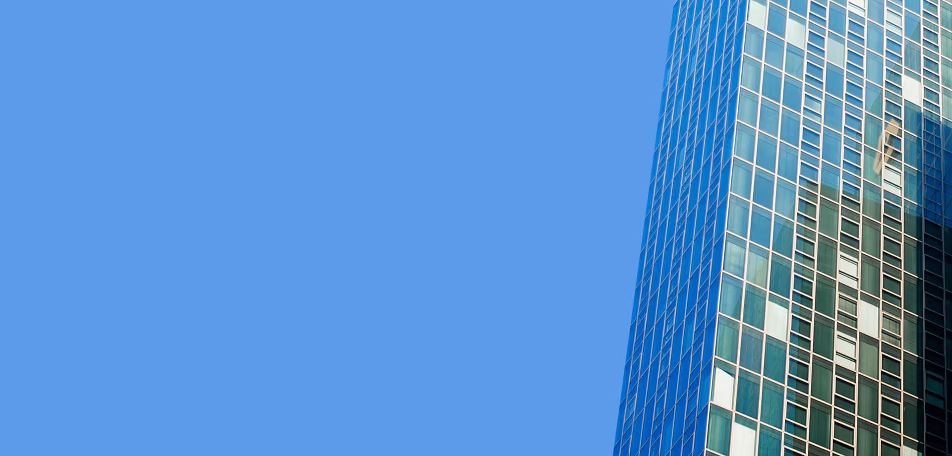 Close-up of a modern glass skyscraper against a clear blue sky.