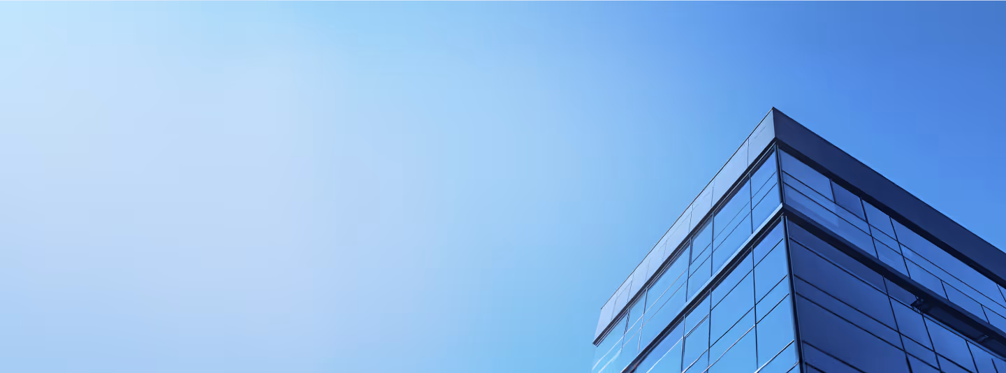 Corner of a modern glass office building under clear blue sky.