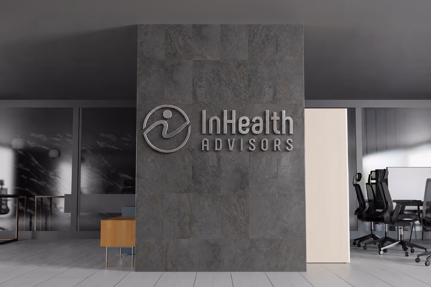 Office lobby wall with InHealth Advisors logo and modern office chairs in the background.