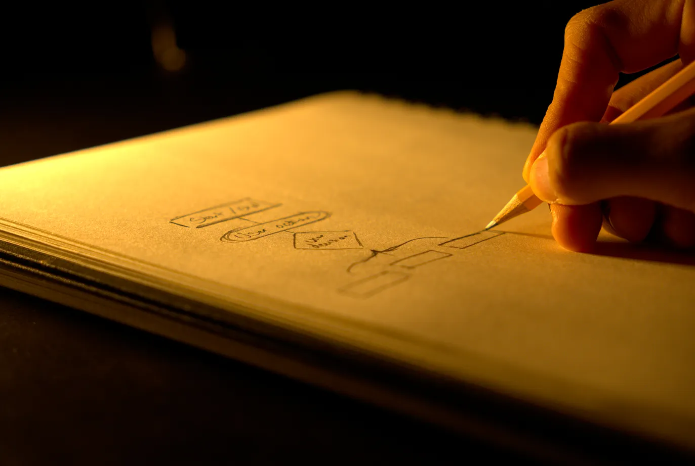 Man drafting a flow chart on his notebook laying out a visualization for a website's user experience.
