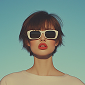 Portrait of a woman with short dark hair wearing white sunglasses and a beige top against a plain background.