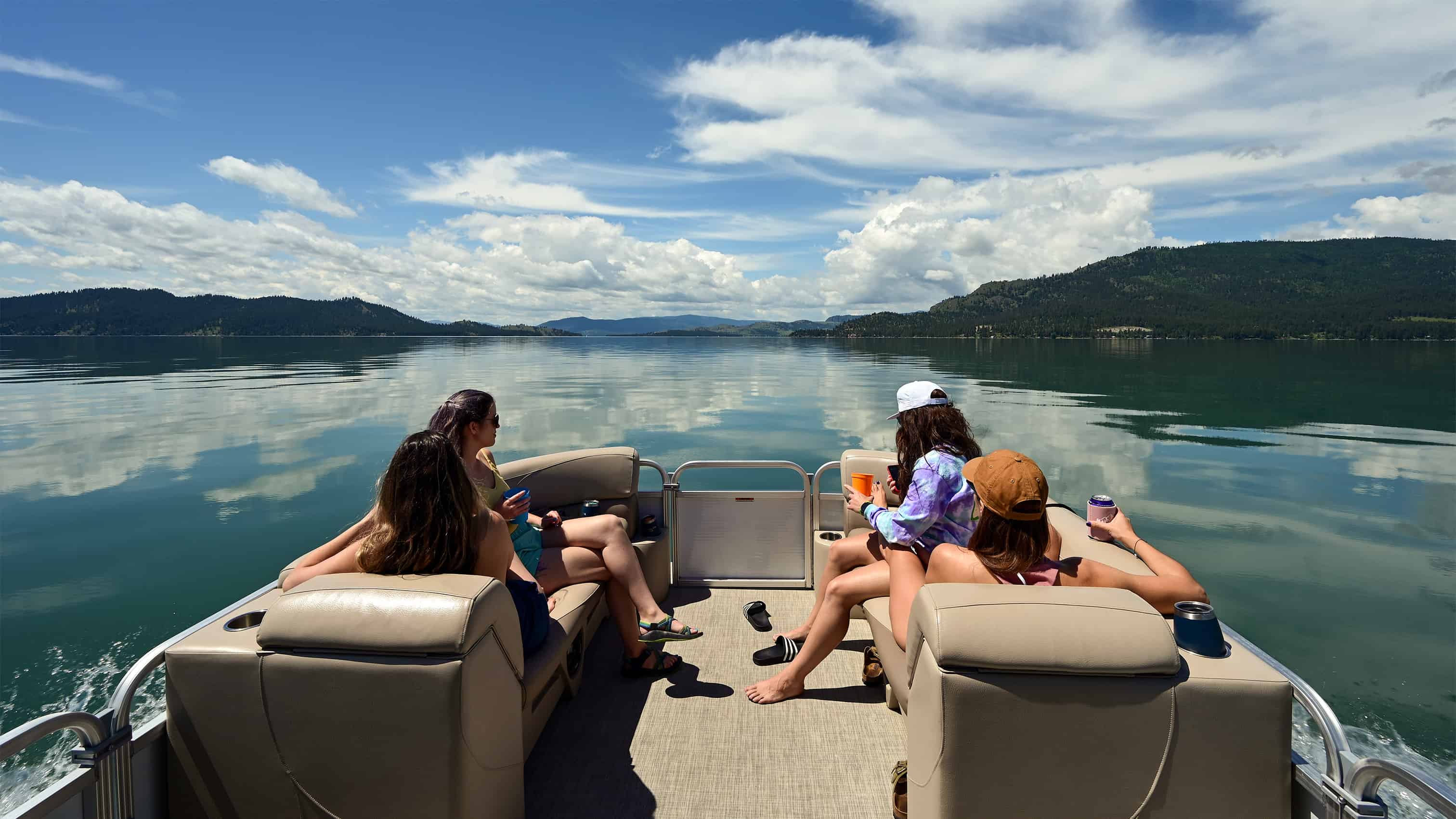 Women relaxing on pontoon boat at Flathead Lake, Montana. Sunny blue skies and clear flat water.