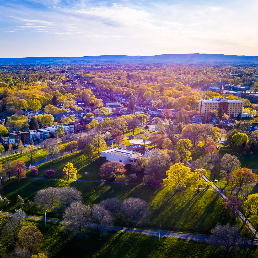 Aerial view of a park with walking paths, mature trees, and surrounding neighborhood in Colonie, NY