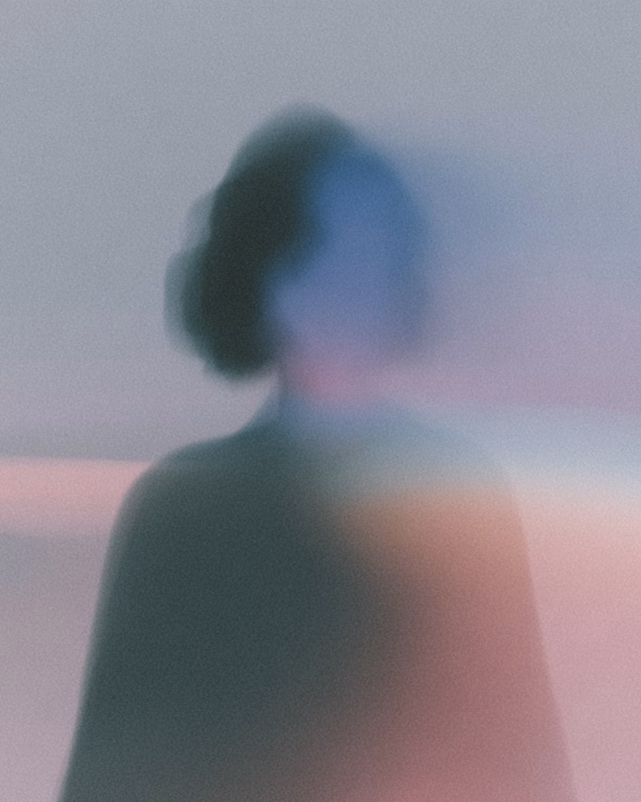 Blurred silhouette of a person with color distortions in soft pastel shades.