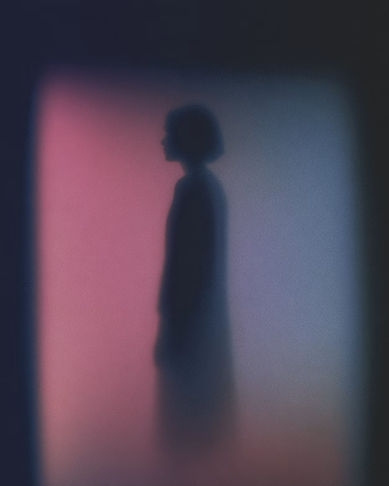 Silhouette of a person with short hair standing against a blurred pink and purple background.