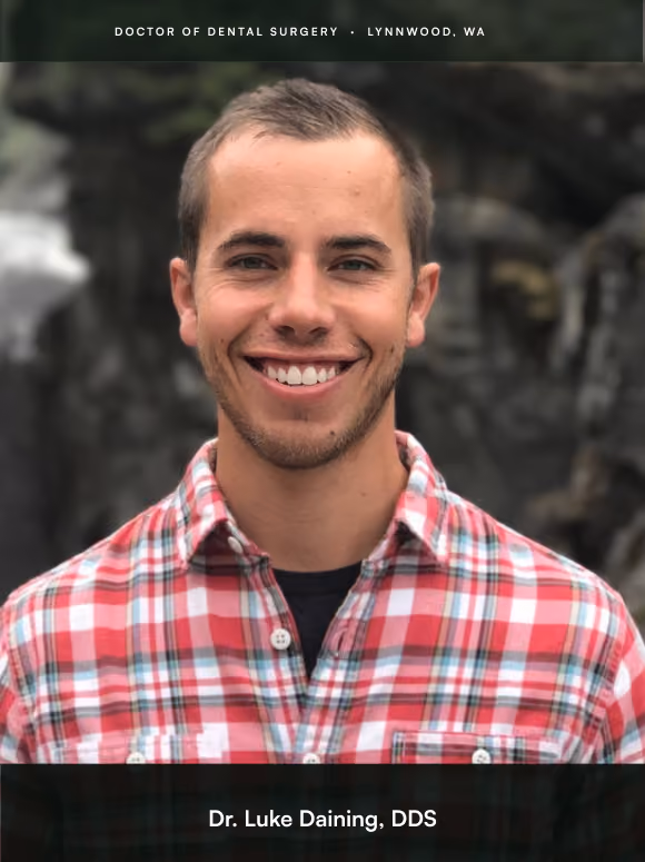 Smiling man wearing a red plaid shirt standing outdoors, labeled Dr. Luke Daining, DDS.