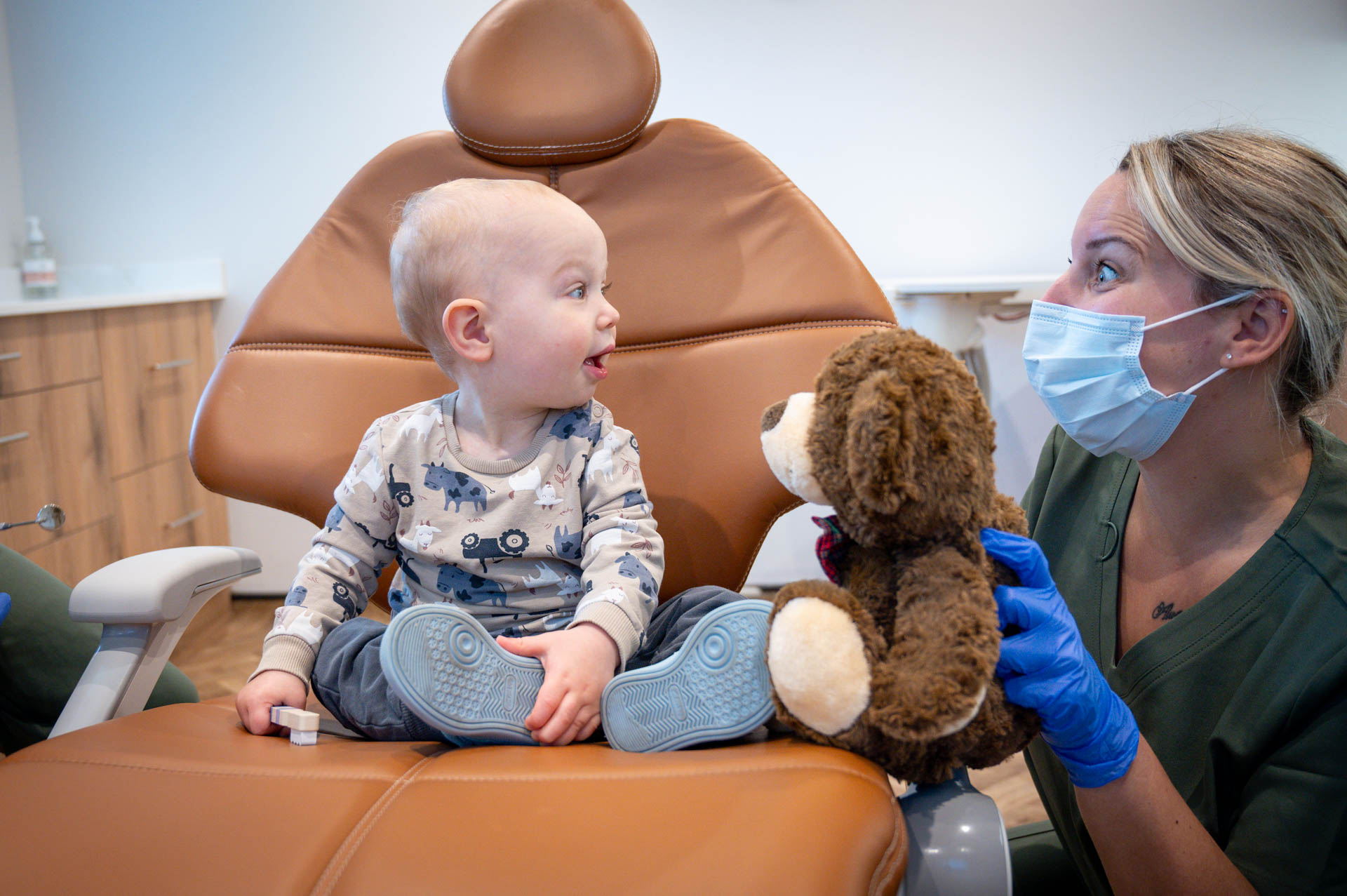 Dentist with a young child and a teddy bear in the dental chair