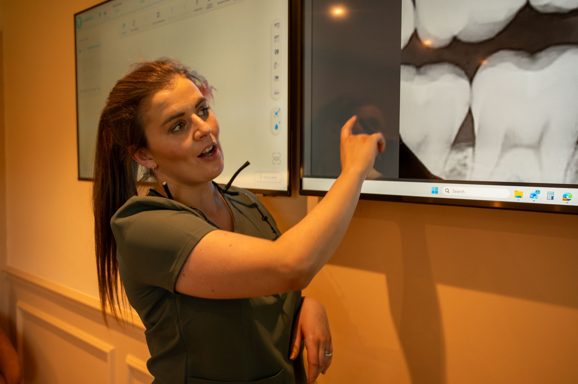 Dentist explaining a dental scan on a large screen