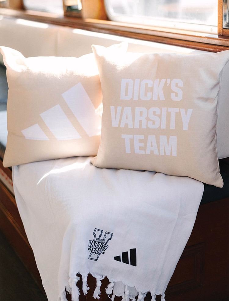Dick’s Varsity Team and Adidas branded pillows and blanket displayed on a bench