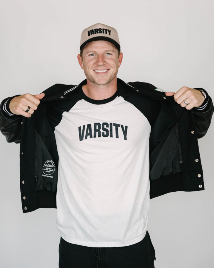 Man wearing a Varsity branded hat and T-shirt with a black jacket