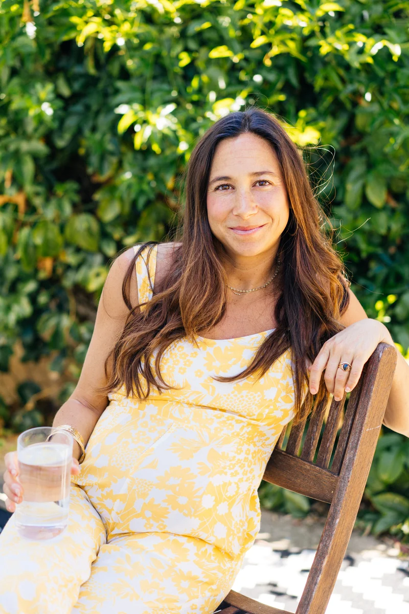 Pregnant woman seated outdoors holding a glass of water
