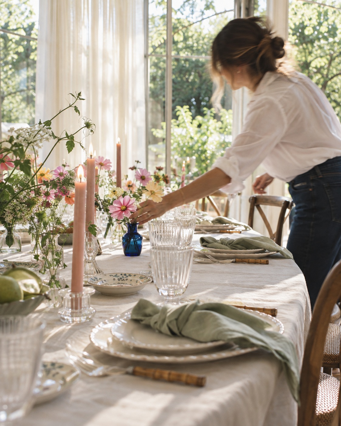 An event planner arranging flowers on a naturally lit celebration table