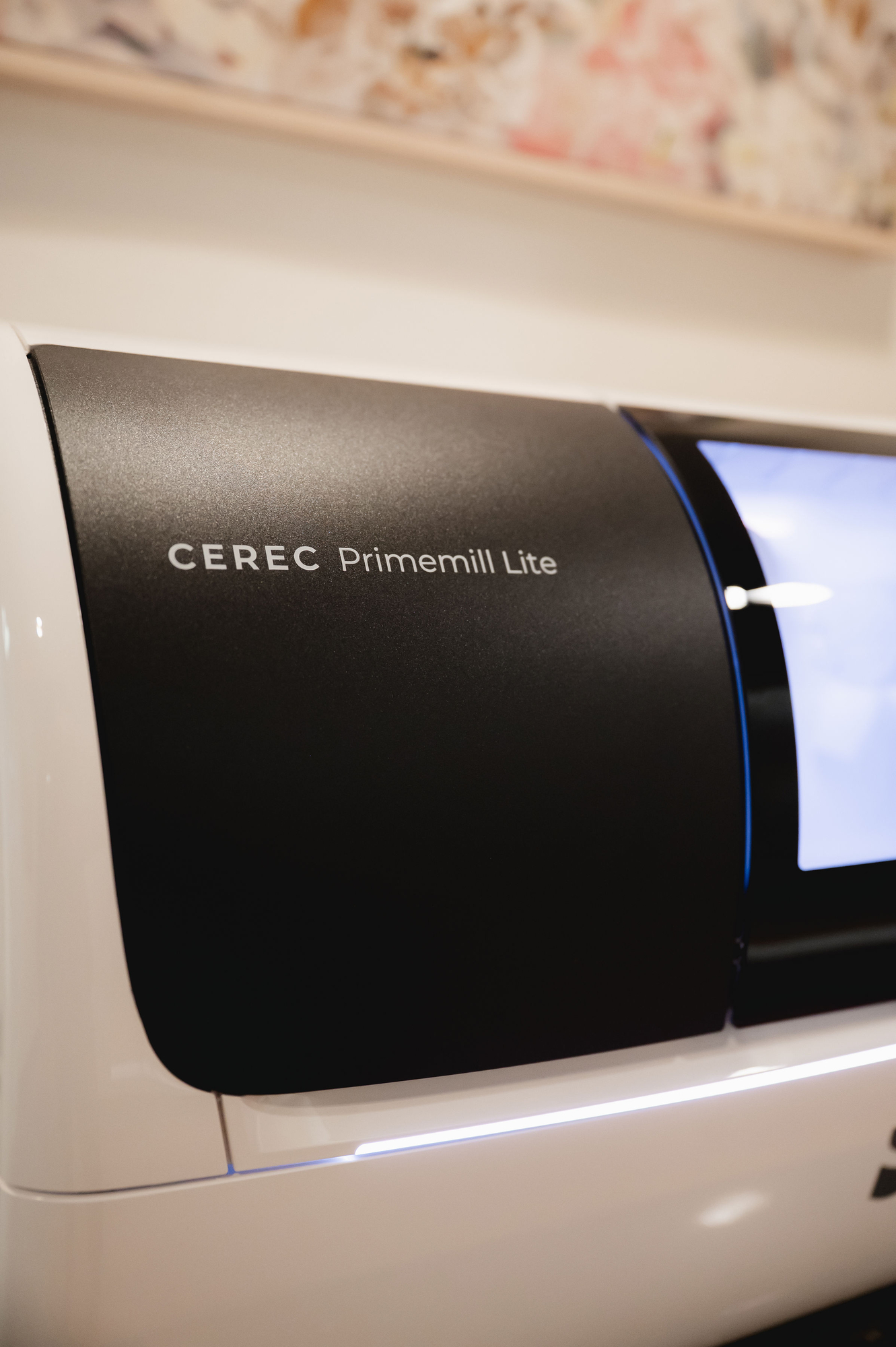 Close-up of CEREC Primemill Lite dental milling machine with black and white casing.