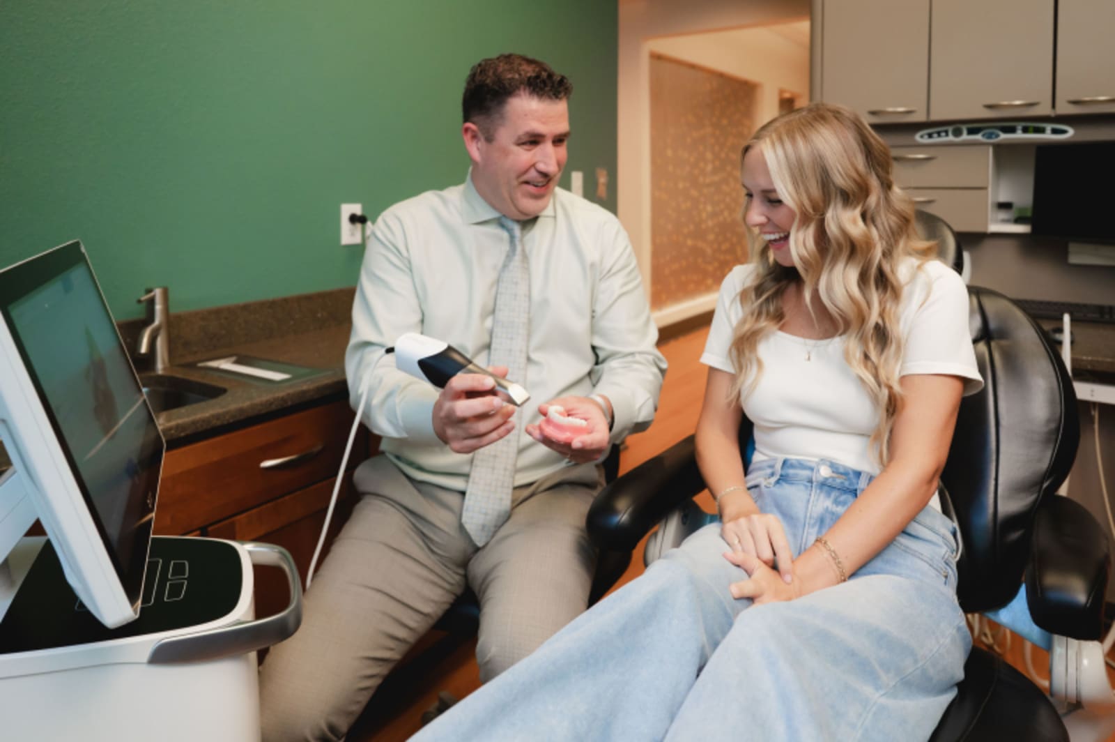 Dentist consulting with patient in treatment room, reviewing exam findings together
