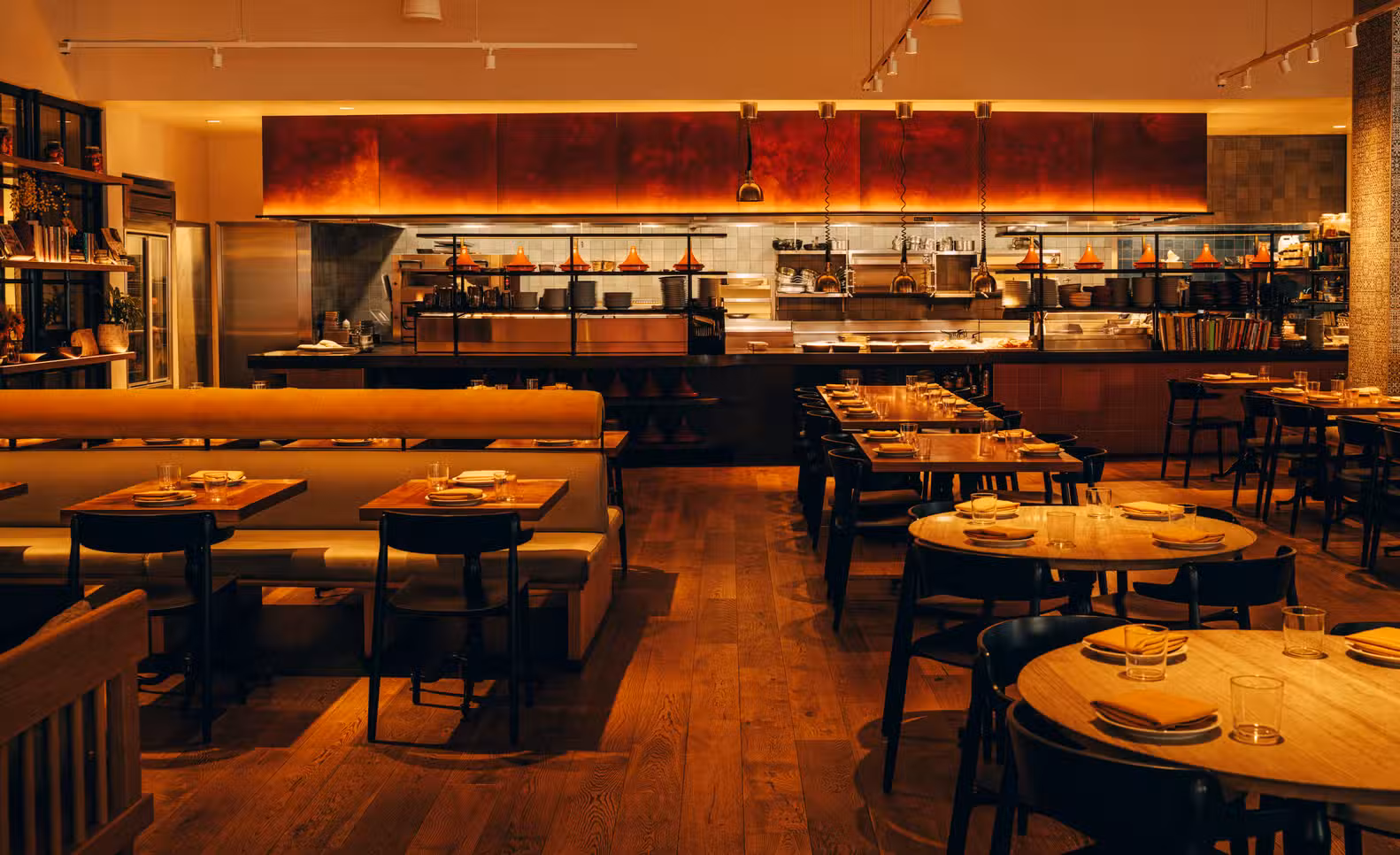 Warm restaurant dining room with an open kitchen