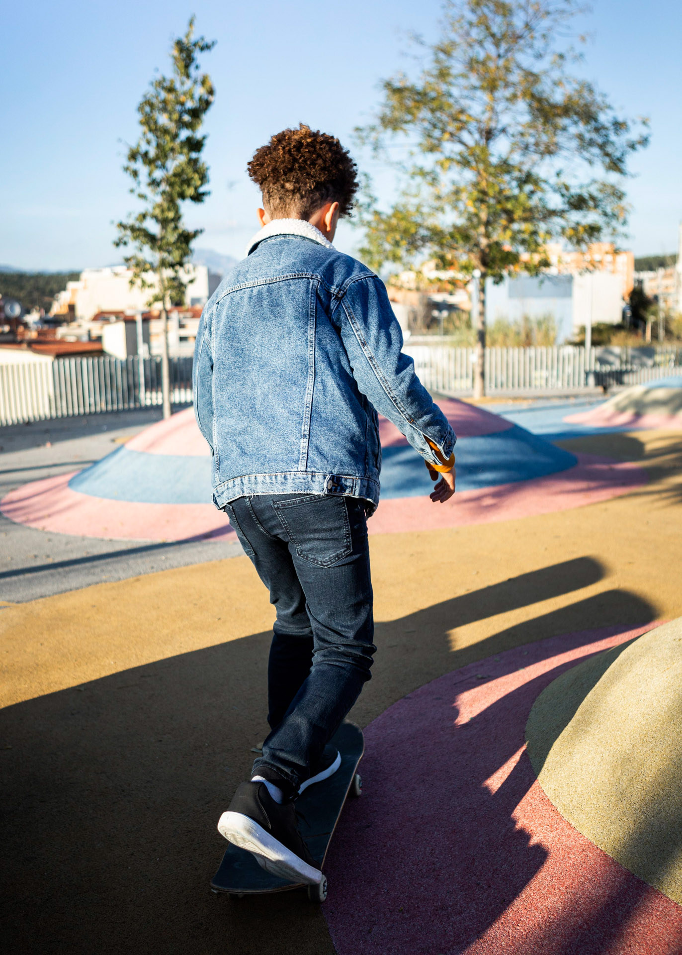 Back view of boy skateboarding at a colorful park on a sunny day.