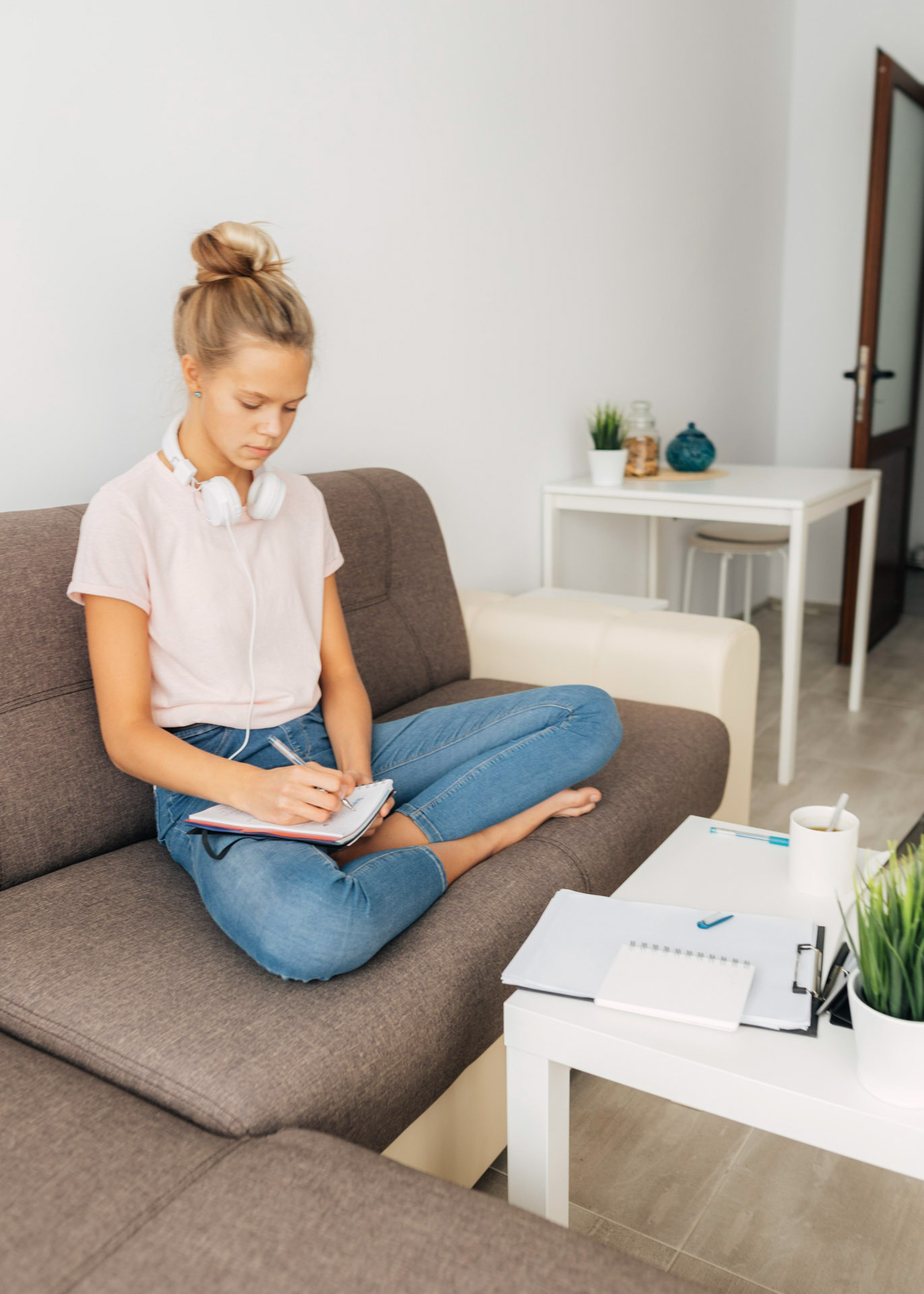 Young girl sitting cross legged on a couch in a living room.