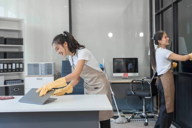 Commercial cleaners servicing a Darwin office — wiping a desk and cleaning glass.