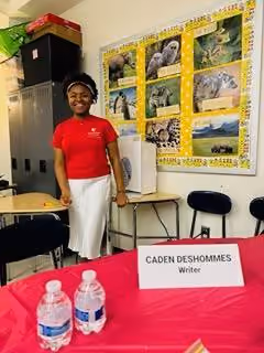 Student Caden Deshommes standing at writer showcase table